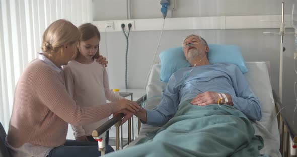 Upset Grandmother and Granddaughter Visiting Dying Patient in Hospital alt