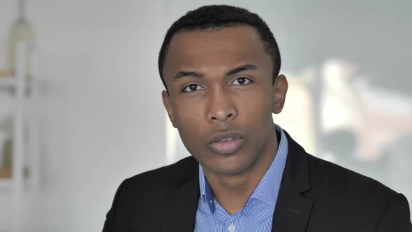 Portrait of Casual AfroAmerican Businessman Gesturing Silence Finger on Lips alt