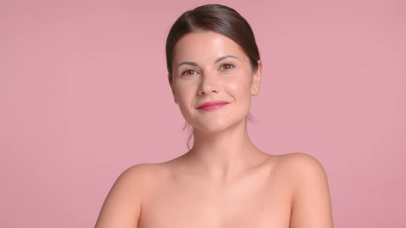 30s Brunette Woman Wears a Decollete Top with Ideal Skin in Studio on Pink Background Natural Makeup