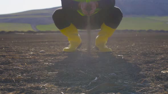 The engineer takes the soil with his handful and pours it. alt