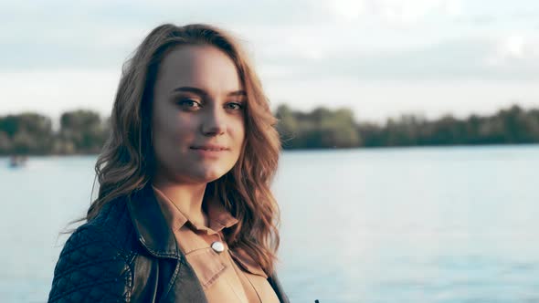 Portrait of a Beautiful Young Woman Drinking Coffee on a Walk Near the River alt