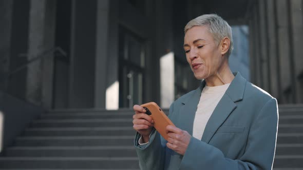 Portrait of Happy Business Woman Enjoy Success on Smartphone Near Office Centre Surprised Caucasian alt