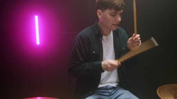 Drummer Playing the Drum Set in a Dark Room on a Black Background alt