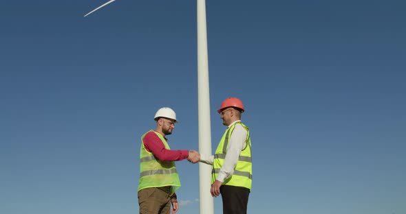 Engineers Shake Hands. In the Background - an Air Windmill alt