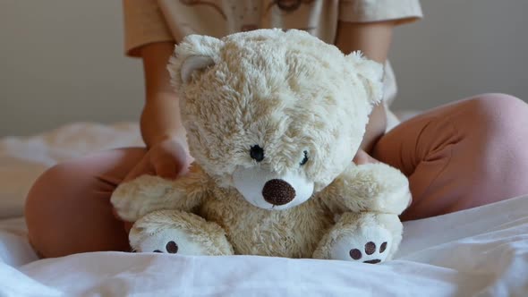 A little girl is holding a teddy bear. alt