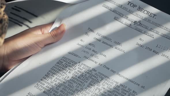 An Undercover Spy Woman Examines Confidential Documents alt
