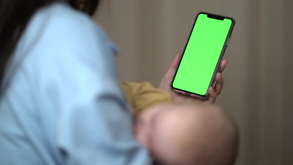 Mother with Sleep Baby Having Video Chat Using Smartphone