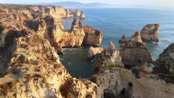 Aerial view of man standing on cliff above beautiful formations, Lagos alt
