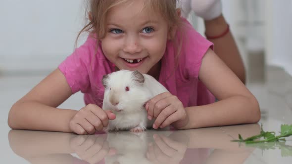 Little Girl Lying on Floor and White Guinea Pig