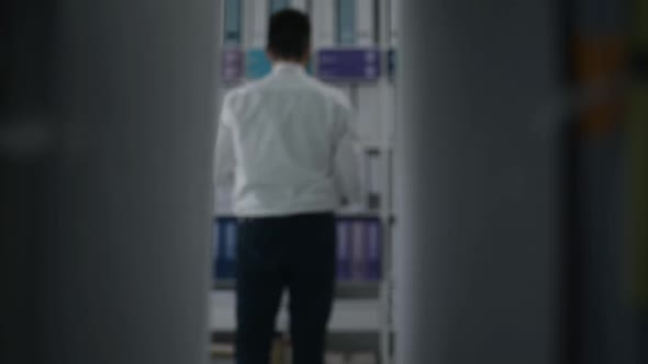 Office worker taking paperwork from a shelf