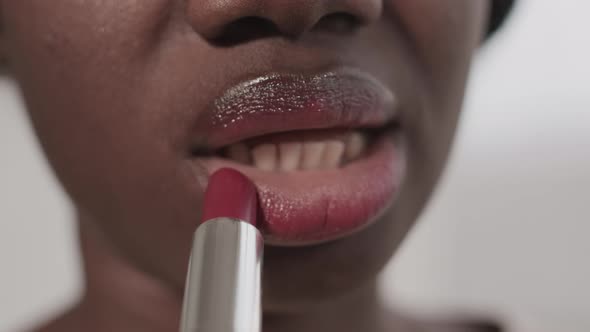 Unrecognizable African-American Woman Applying Lipstick alt