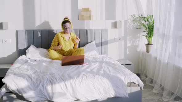 Positive Lady in Pajamas with Mask Dancing on Bed