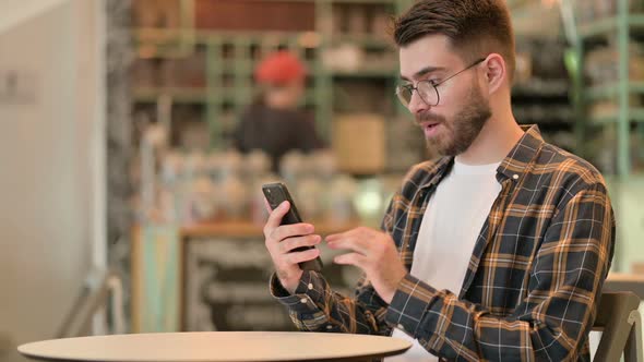 Ambitious Young Man Celebrating Success on Smart Phone alt