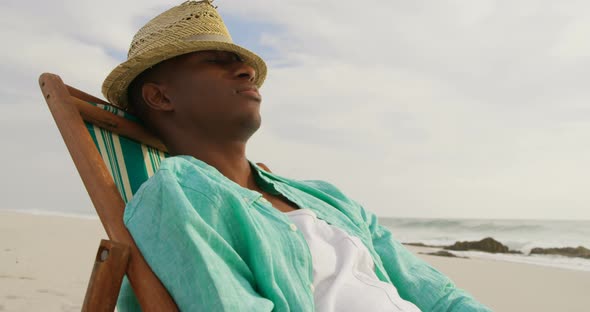 Side view of African american man sleeping in a sun lounger on the beach 4k alt