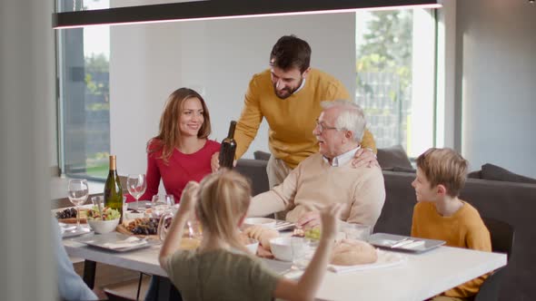 Happy family having a dinner with red wine at home