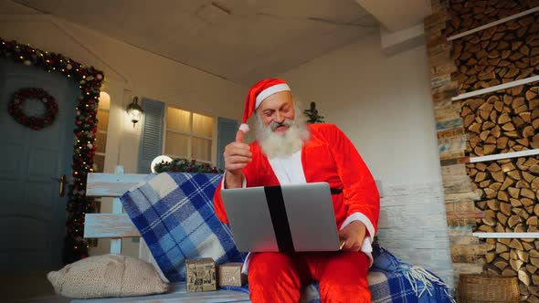 Funny Santa Claus Showing Thumbs Up and Working with Laptop.