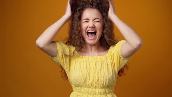 Portrait of Beautiful Young Woman Shaking Her Hair Against Yellow Background