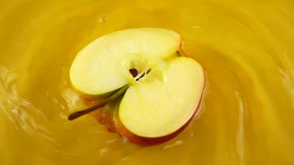 Rotating segments of a ripe and juicy apple on an orange background. Slow motion. alt
