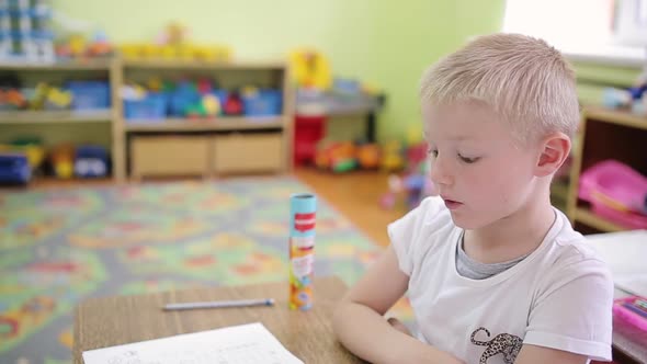 A Boy in a Plaid Shirt Sits on a Chair in Front of the Camera with a Microphone on His Clothes