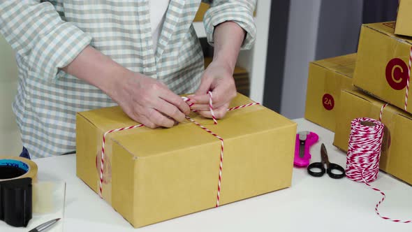 hand of woman entrepreneur are tying ropes and packing products in parcel box