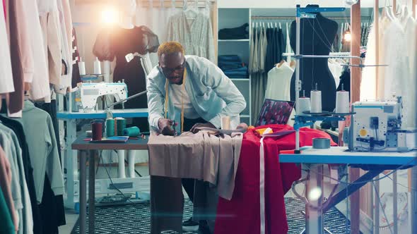 African Tailor is Cutting Out a Piece of Fabric alt
