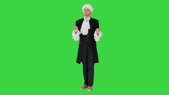 Man Dressed in Courtier Frock Coat and White Wig Thinking and Fidgeting with His Fingers on a Green Screen alt