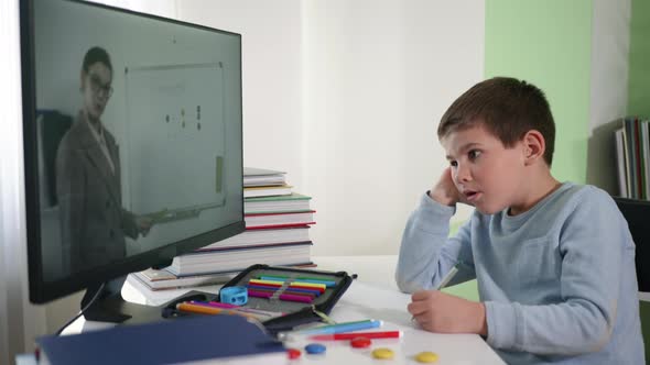 Online Teaching, Schoolboy at Home Watching a Video Broadcast with His Teacher Explains Lesson on alt