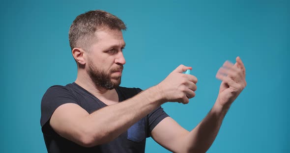 Muscular Man in Black Tshirt Sprays Antiseptic on Hands alt