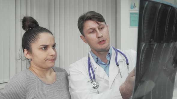 Experienced Doctor Showing Xray Scan to Female Patient alt
