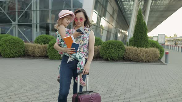Mother and Daughter Near Airport. Woman Hold Passports and Tickets in Hand. Child and Mom Vacation alt