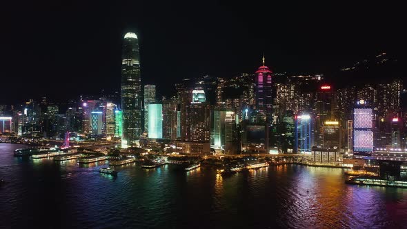 Hong Kong night aerial view of Hong Kong island, boats sailing on Victoria Harbour. Panning forwards alt