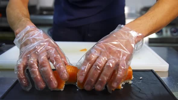Chef in restaurant prepares sushi rolls with salmon, rice and and avocado. Delicious asian food. alt