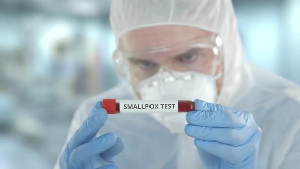 Defocused Laboratory Assistant Examines Vial with Smallpox Test alt
