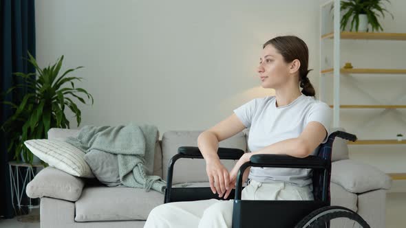 Portrait of Young Woman Sitting in Wheelchair at Home with Light Smile alt