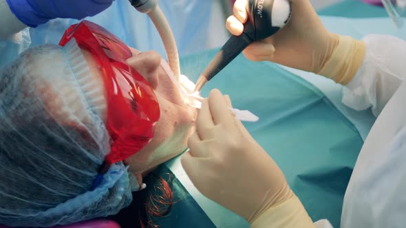 Female Patient in Protection Glasses is Having Her Teeth Treated alt
