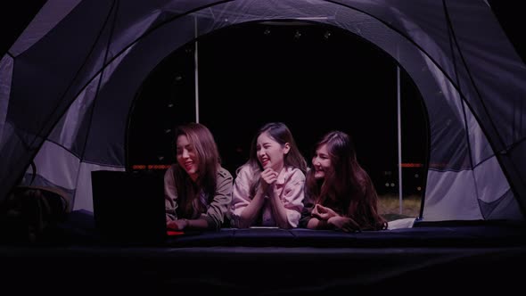 at night,Asian young women group friend are enjoy using a laptop to search the internet
