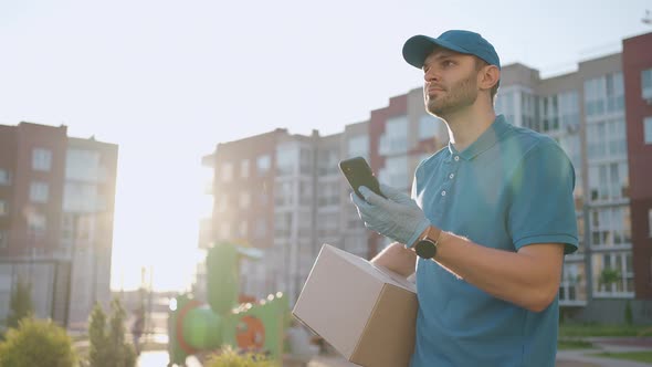 Male Courier Man is Looking for Mobile Phone to Deliver Address of Food From a Shop alt