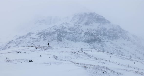 Solo mountaineer caught up in a strong blizzard on a winter day
