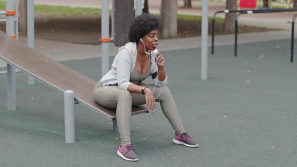 African American Woman Talking through Earphones at Sports Ground alt