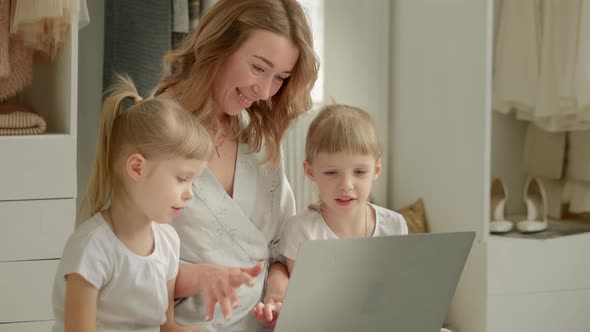 Mom with Daughters Blonde Twins Sitting at a Laptop