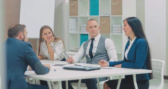 Group of Businessmen Met at a Negotiating Table in a Modern Coworking Center. Young Men and Women