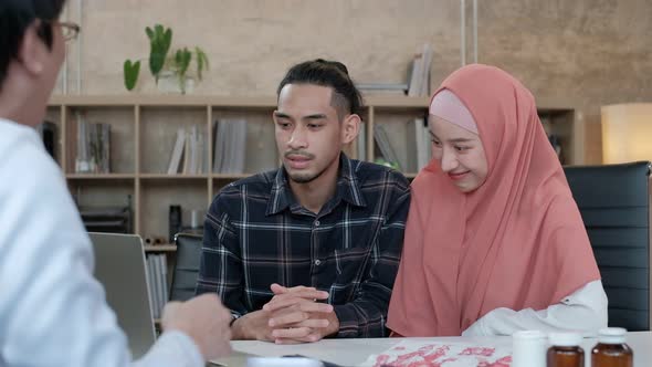 Young Muslim couple consulting with professional Asian male doctor. alt
