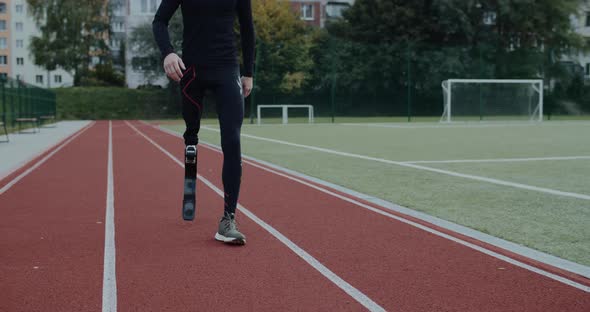 Crop View of Disabled Male Person with Prosthetic Blade Walking at Sports Field alt