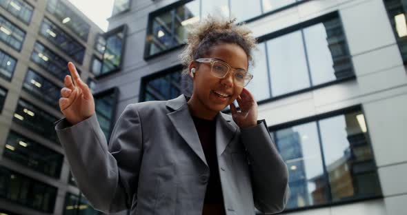 A Woman Wearing Headphones Listens to Music and Dances Outside Office Building alt
