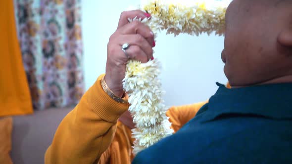 Happy Indian Wife Putting On A White Floral Garland To Her Husband At Home In Agra India Medium Shot alt