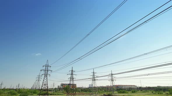 Four Power Energy Lines of Highvoltage Transmission Pylons with Industrial Background and Clear Blue