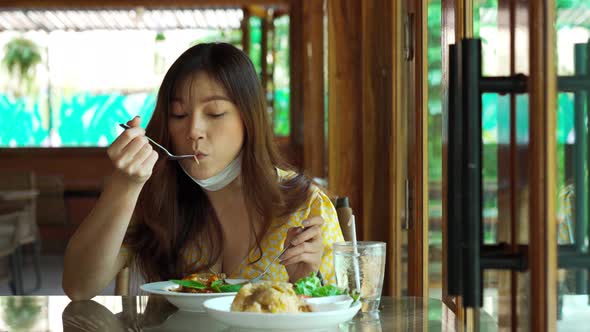 young woman with face mask eating spaghetti food in restaurant, New normal concept