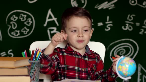 Cute boy doing homework, coloring pages, writing and painting. Children paint. Kid draw alt