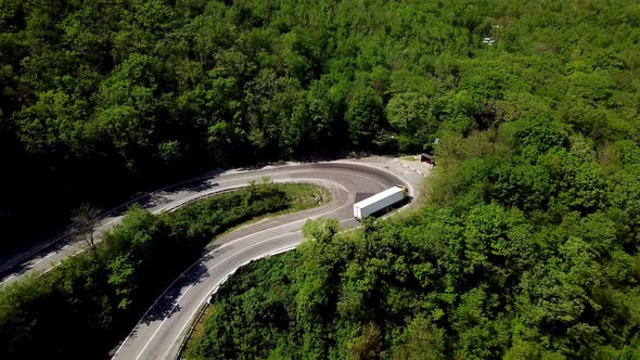 FPV Semi Truck Driving Along Mountain Road Going Through Forest Landscape alt