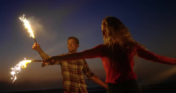Couple dancing with sparklers on beach at dusk 4k